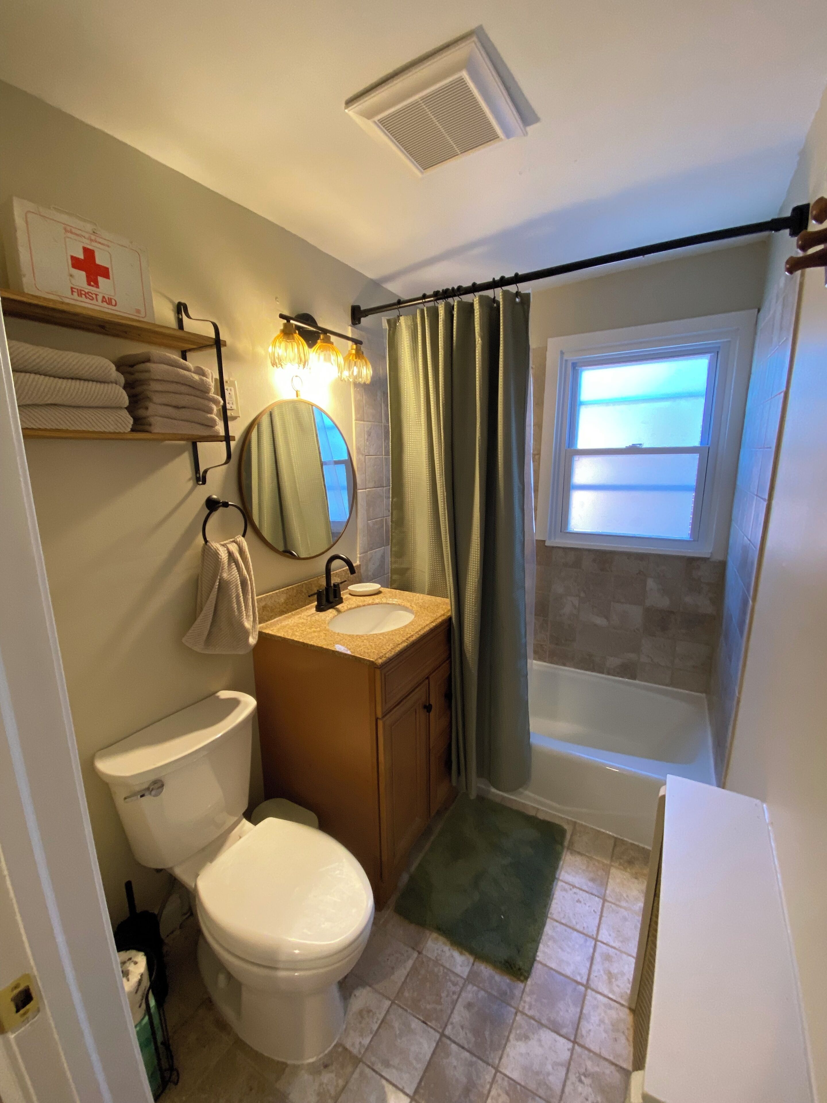 A bathroom with a toilet, sink, mirror, and shower curtain.