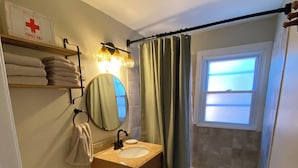 Et badeværelse med toilet, vask, spejl og bruseforhæng.