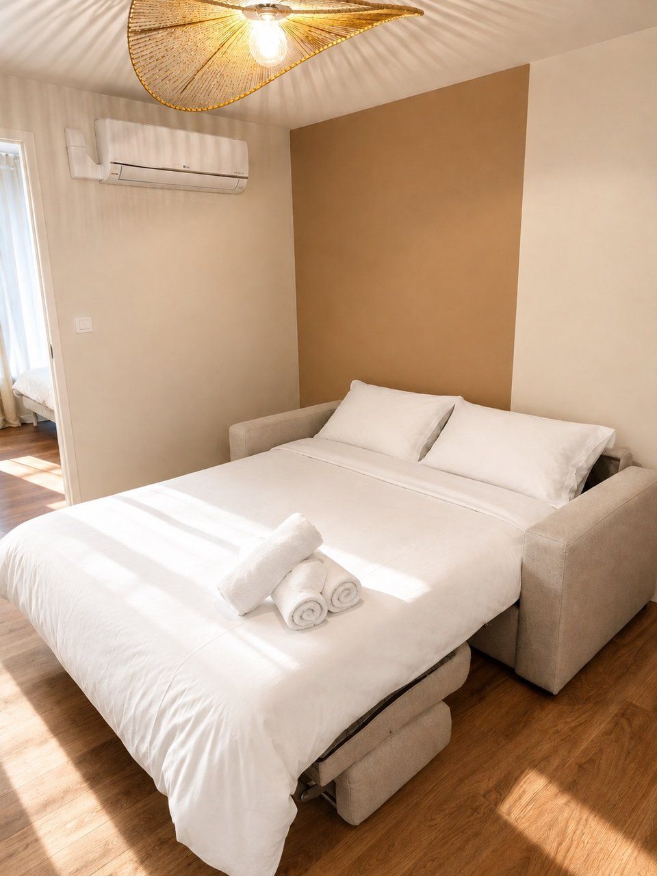A modern bedroom with a bed, a ceiling light fixture, and an air conditioning unit.