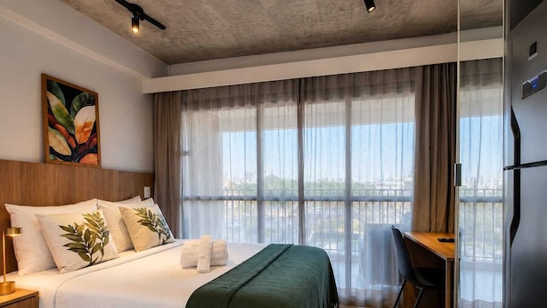 Ein Hotelzimmer mit Bett, Schreibtisch und Blick auf die Stadt.