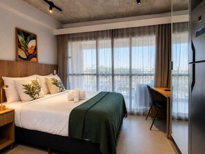 A hotel room with a bed, a desk, and a view of the city. - Premium Studio Augusta | Next Oscar Freire (São Paulo)