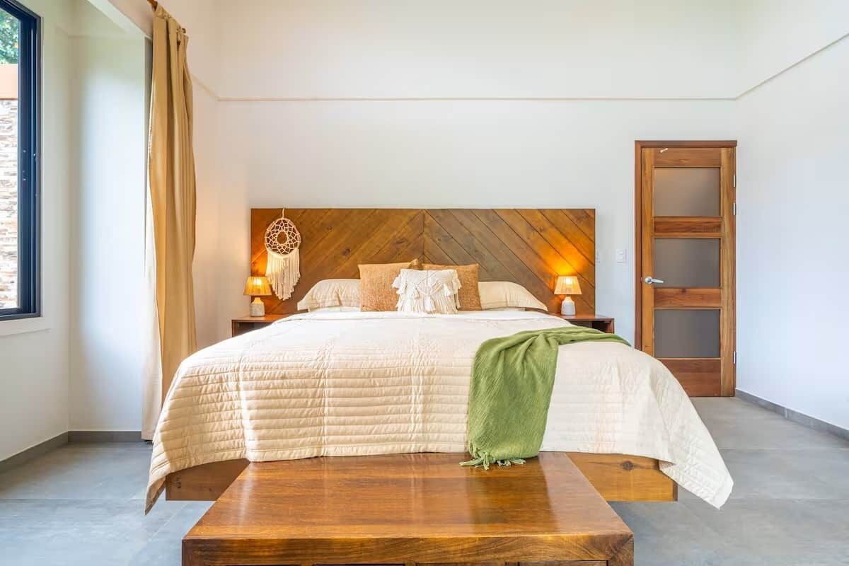 A bedroom with a large bed, wooden headboard, bedside lamps, and a wooden nightstand.