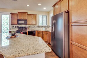 Una cocina con armarios de madera, un refrigerador de acero inoxidable, un microondas y una encimera de granito.