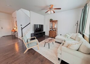 A living room with a sofa, a coffee table, a TV, a wooden cabinet, and a staircase. - Feel at Home in Stone Oak @great for Weeks/Months /3 beds 2.5 baths- Gated (San Antonio)