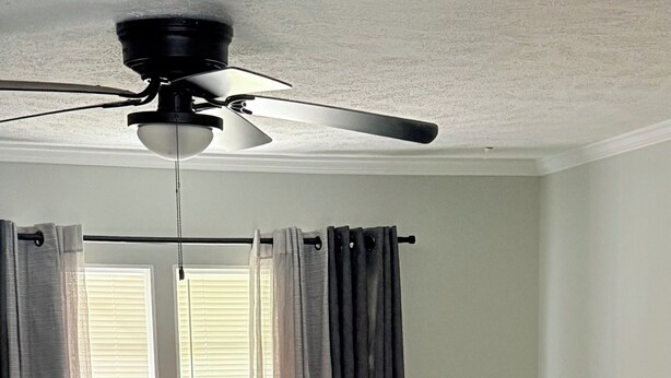 A living room with a ceiling fan, a sofa with patterned cushions, a round table, and a large plant. - The Cove #2. Lovely 2-bedroom apartment with AC in charming Rockingham. (Rockingham)