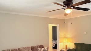 A living room with a sofa, a round coffee table, a ceiling fan, and a lamp. - The Cove #2. Lovely 2-bedroom apartment with AC in charming Rockingham. (Rockingham)
