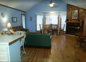 A living room with a sofa, a dining table with chairs, a fireplace, and a ceiling fan. - Big Cottage, sleeps 21 close to Lake Ouachita! (Mount Ida)