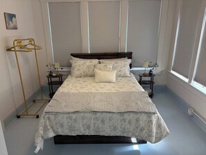 A bedroom with a bed, two bedside tables, a floor lamp, and a window with blinds. - Renovated Apartment Downtown HS (Hot Springs)