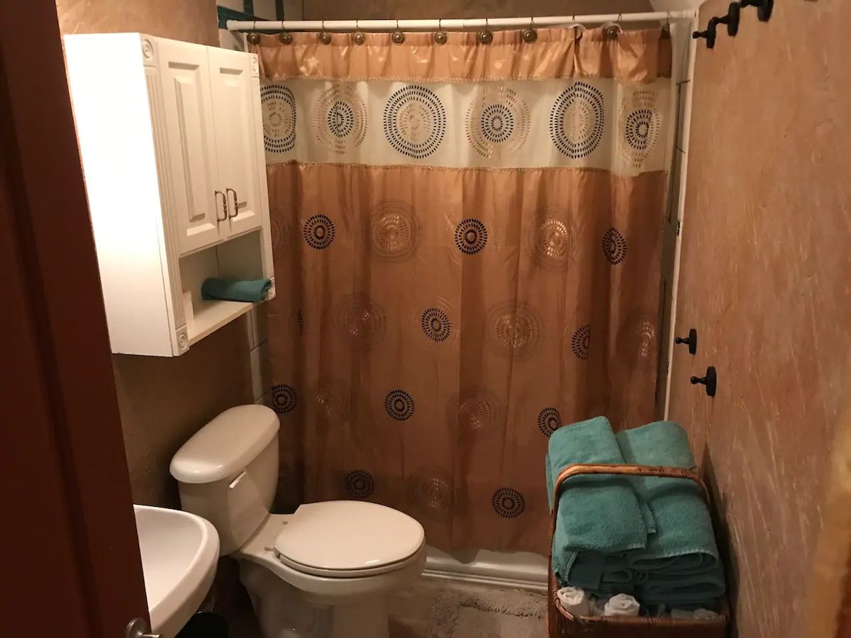 A bathroom with a toilet, a shower curtain, and a towel rack.