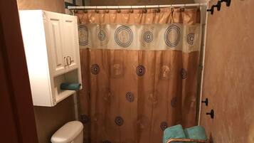 A bathroom with a toilet, a shower curtain, and a towel rack.