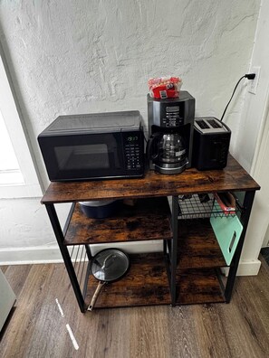 A kitchen area with a microwave, coffee maker, and toaster on a wooden stand. - The Hideout downtown Hot Springs (Hot Springs)