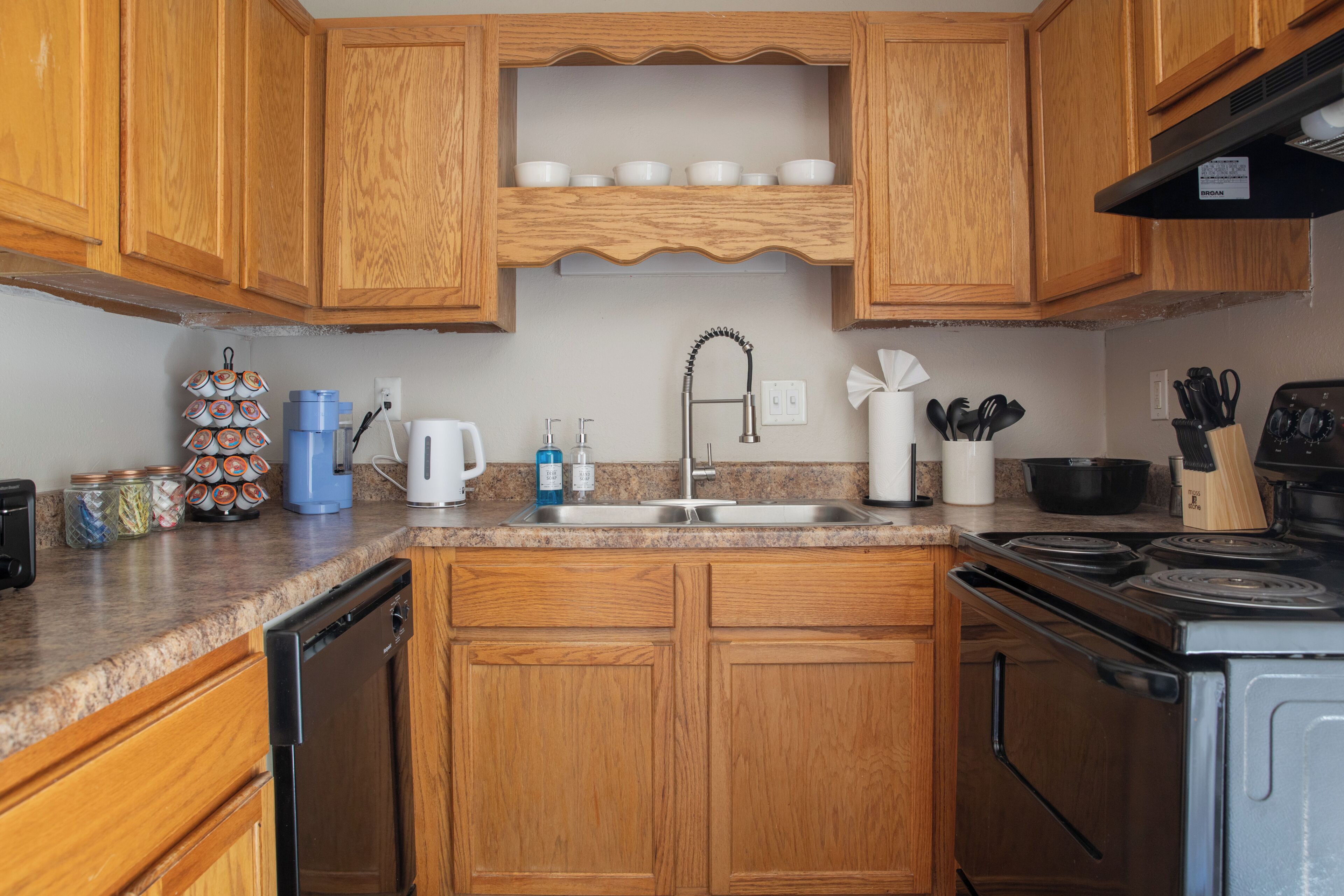 A kitchen with wooden cabinets, a stainless steel sink, a stove, and various kitchen appliances.