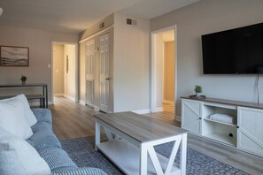 Ein modernes Wohnzimmer mit einer Couch, einem Couchtisch und einem an der Wand befestigten Fernseher.