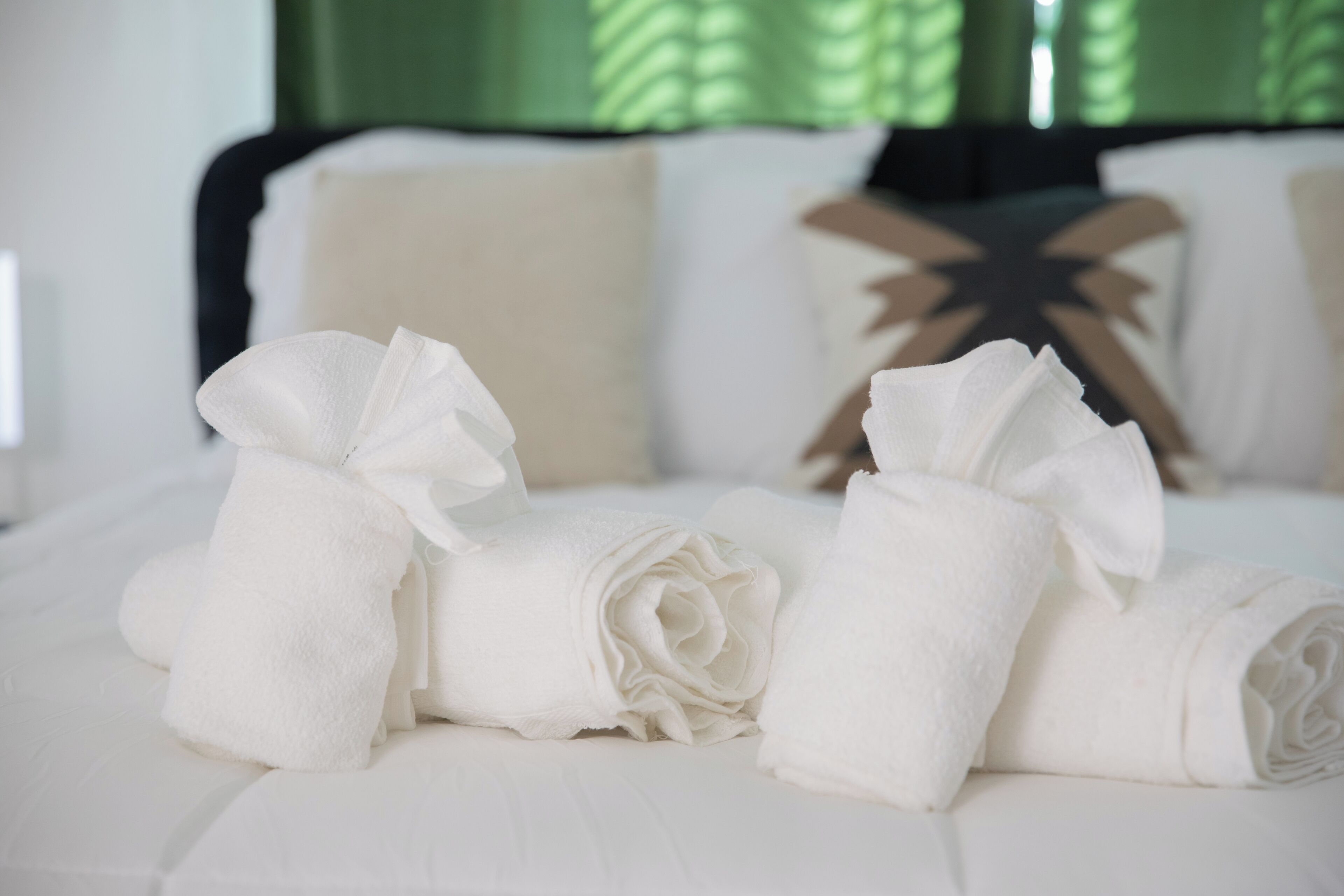 Un lit bien fait, avec du linge de lit blanc et des coussins décoratifs.