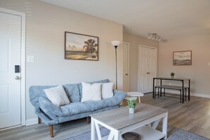 Un salon avec un canapé, une table basse, une lampe et deux portes.