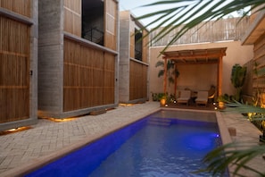 A pool area with a blue pool, wooden fences, and a seating area with chairs and plants. - Jilöo- Beautiful Oasis in Punta Zicatela (7) (Punta Zicatela)
