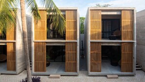 Un bâtiment moderne composé de structures à deux étages, chacune dotée d’un balcon et d’une façade à lamelles de bois.
