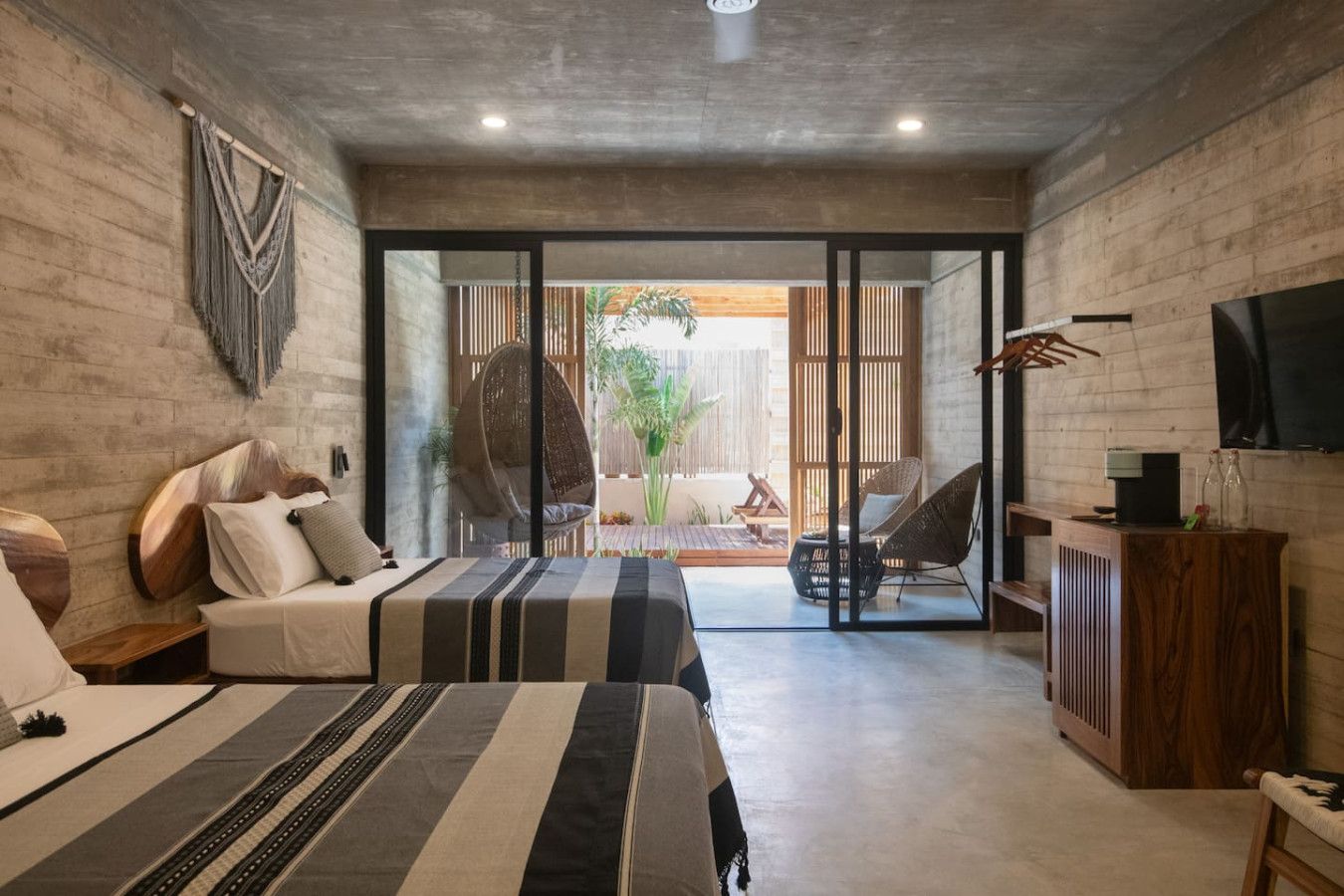 A modern bedroom with a bed, bedside tables, a TV, and a view of the outdoors.