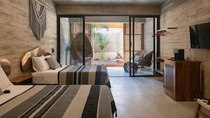 Quarto moderno com cama, mesas de cabeceira, televisão e vista para o exterior.