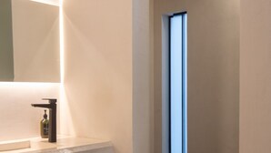 Une salle de bain moderne avec un grand miroir, un lavabo et une fenêtre.