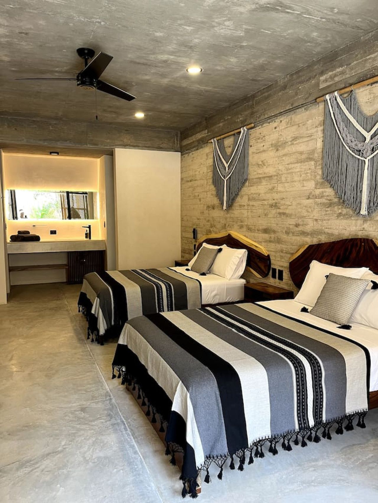 A bedroom with two beds, a vanity, and a ceiling fan.