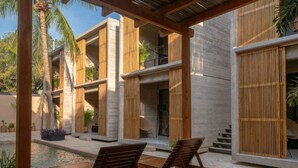 Ein moderner Außenbereich mit Pool, Holzliegen und einem Gebäude mit großen Fenstern und Holzlamellen.