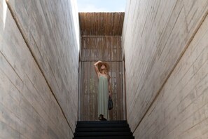 A person standing in a narrow corridor with wooden walls and a staircase leading upwards.
