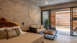 A modern bedroom with a wooden headboard, a sofa, a coffee table, and a large window. - Jilöo - Beautiful Oasis in Punta Zicatela (5) (Punta Zicatela)