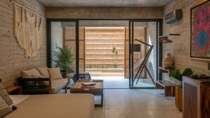 A modern living room with a sofa, coffee table, and a view of a wooden deck and outdoor plants. - Jilöo - Beautiful Oasis in Punta Zicatela (5) (Punta Zicatela)