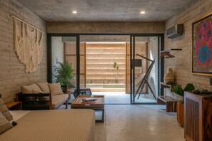 A modern living room with a sofa, coffee table, and a view of a wooden deck and outdoor plants. - Jilöo - Beautiful Oasis in Punta Zicatela (5) (Punta Zicatela)