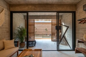 A modern interior with a sofa, coffee table, and a view of an outdoor pool area through a glass door.