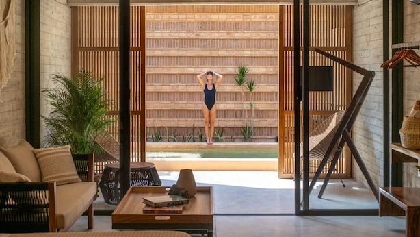 A modern interior with a sofa, a dining table, a hammock, and a view of a pool area. - Jilöo - Beautiful Oasis in Punta Zicatela (5) (Punta Zicatela)