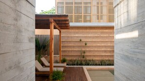 Une terrasse extérieure moderne avec une plateforme en bois, des chaises longues, une petite piscine et un mur en bambou.