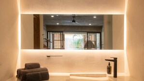 Une salle de bain avec un grand miroir, un lavabo et un porte-serviettes.