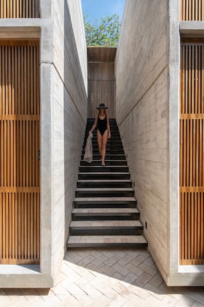 A person descending a concrete staircase with wooden railings on either side.