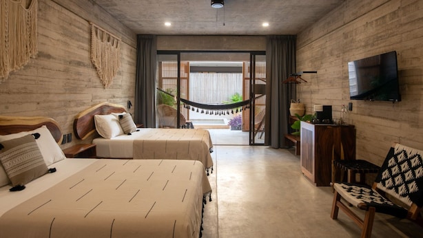 A room with two beds, a hammock, a TV, and a view of the outdoors. - Jilöo - Beautiful Oasis in Punta Zicatela (3) (Punta ZIcatela)