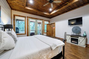 Ein Schlafzimmer mit einem Bett, einem Fernseher, einem Kamin und einem Deckenventilator.