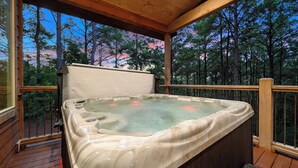 A hot tub on a wooden deck with a view of trees. - Secluded Cabin | Hot Tub | Game Loft (Broken Bow)