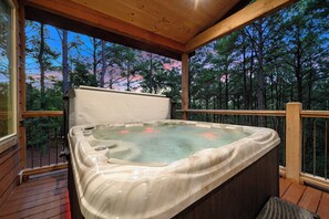 Ein Whirlpool auf einer Holzterrasse mit Blick auf Bäume.