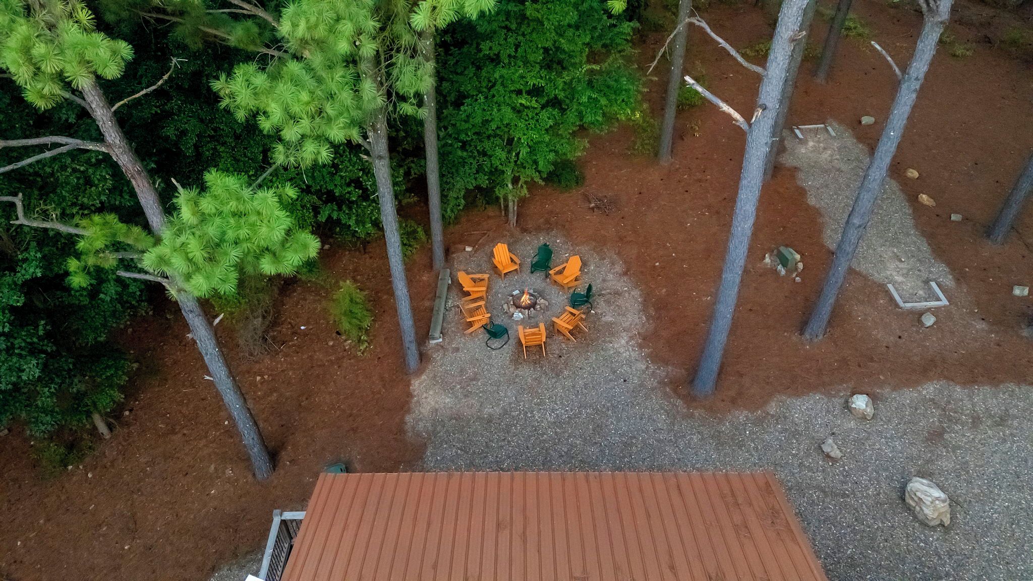 Ein Außenbereich mit Sitzgelegenheiten, wobei Stühle kreisförmig um eine Feuerstelle angeordnet sind.