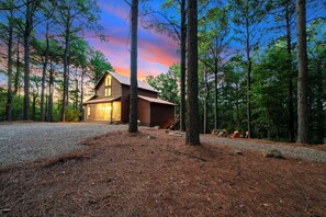 A cabin with a stone foundation, wooden exterior, and a porch with outdoor seating. - Secluded Cabin | Hot Tub | Game Loft (Broken Bow)