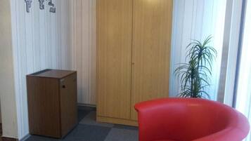 A room with a wooden wardrobe, a red chair, and a potted plant.