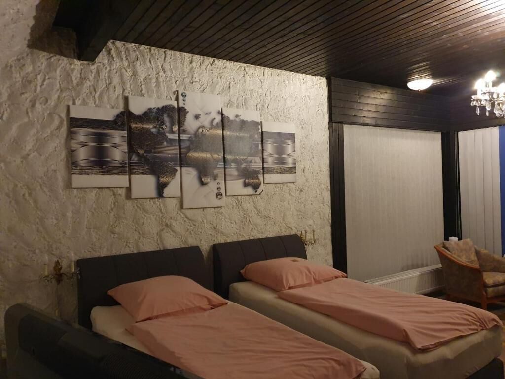 Een slaapkamer met twee bedden, een groot kunstwerk aan de muur, een stoel en een schuifdeur.