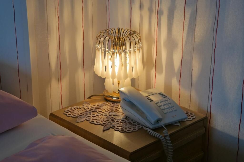 A bedside table with a telephone and a decorative lamp.