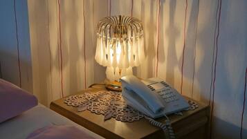 A bedside table with a telephone and a decorative lamp.