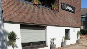 A hotel with a brick facade, a signboard, and potted plants. - Hotel am Hallenbad (Ratingen)