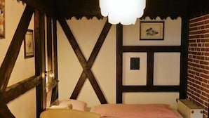 A cozy room with a bed, a chair, a small table, and a hanging light fixture. - Hotel am Hallenbad (Ratingen)