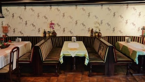 A restaurant with striped booths and tables, floral wallpaper, and a tiled floor. - Hotel am Hallenbad (Ratingen)