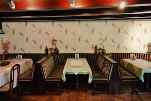A restaurant with striped booths and tables, floral wallpaper, and a tiled floor. - Hotel am Hallenbad (Ratingen)