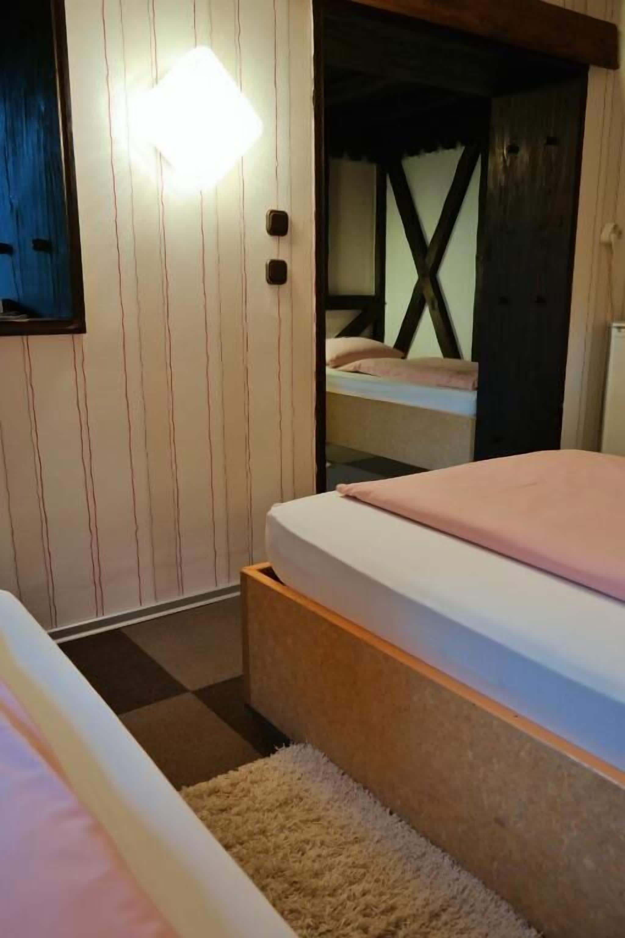 A bedroom with a bed, a bedside table, a nightstand, and a wall-mounted light fixture.